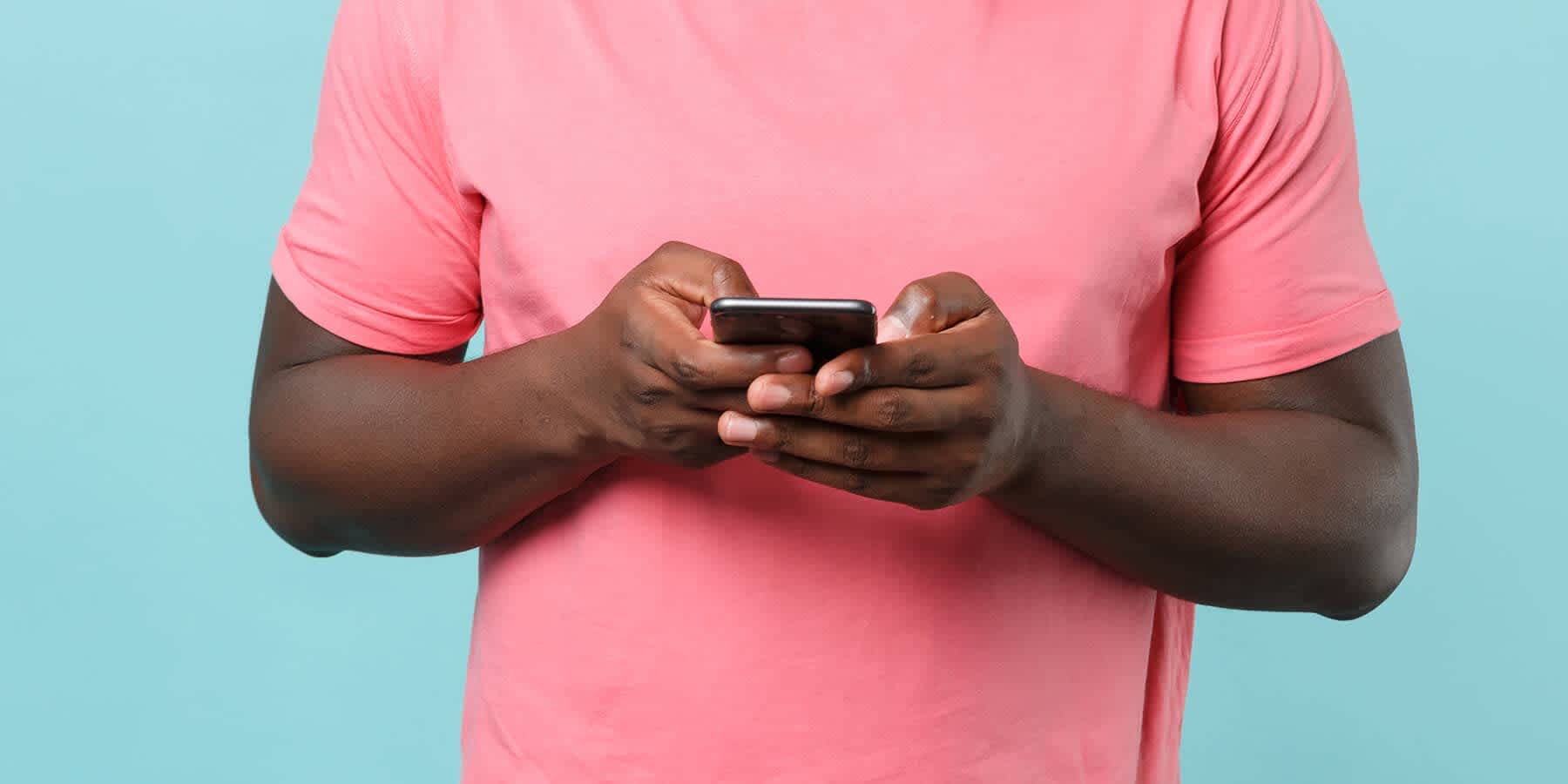 Man in pink shirt against a blue background researching if molluscum contagiosum is an std on a mobile phone