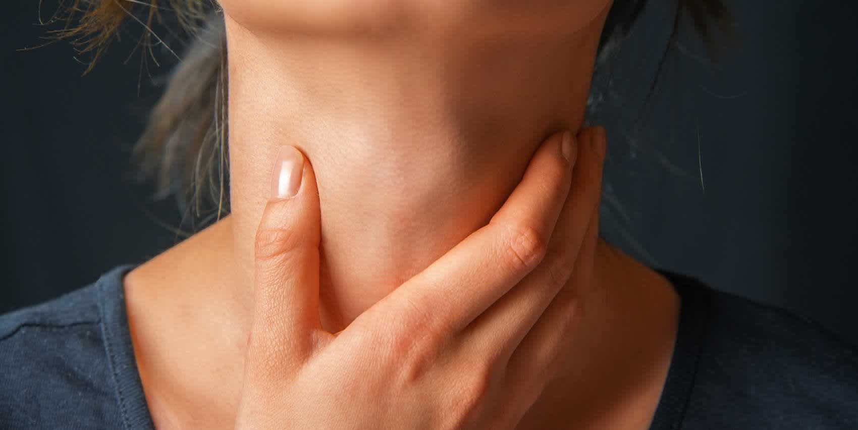 Woman cupping her neck with her hand while wondering about chlamydia in the throat