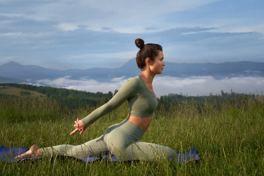woman posing on a yoga mat in a field