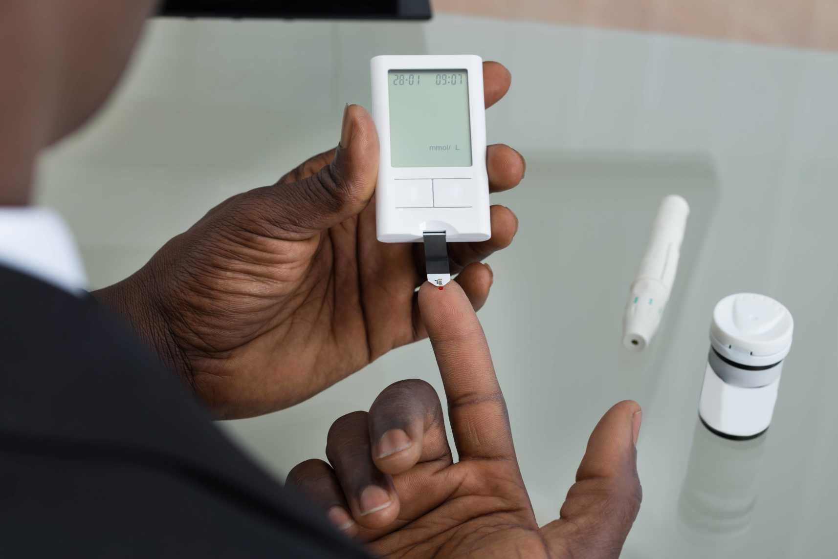 Man with headache checking for high blood sugar with glucometer