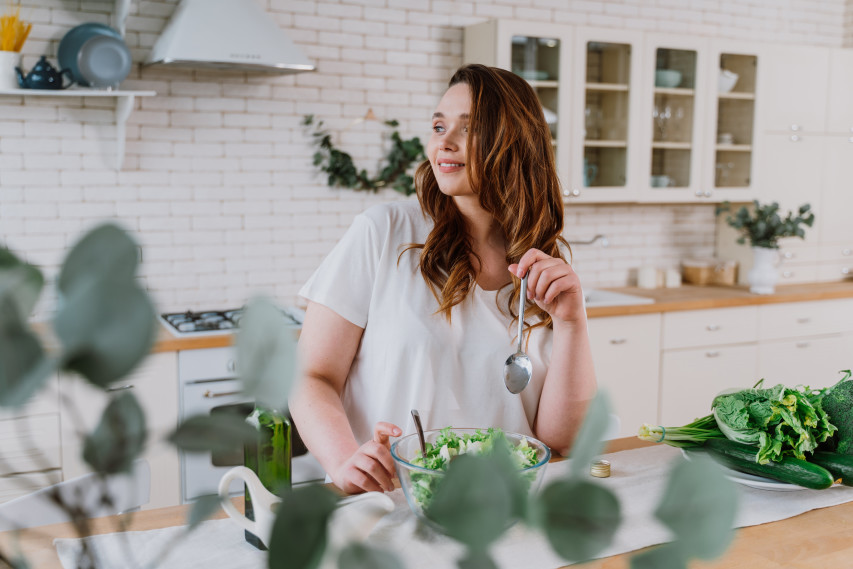 woman in kitchen eating a salad