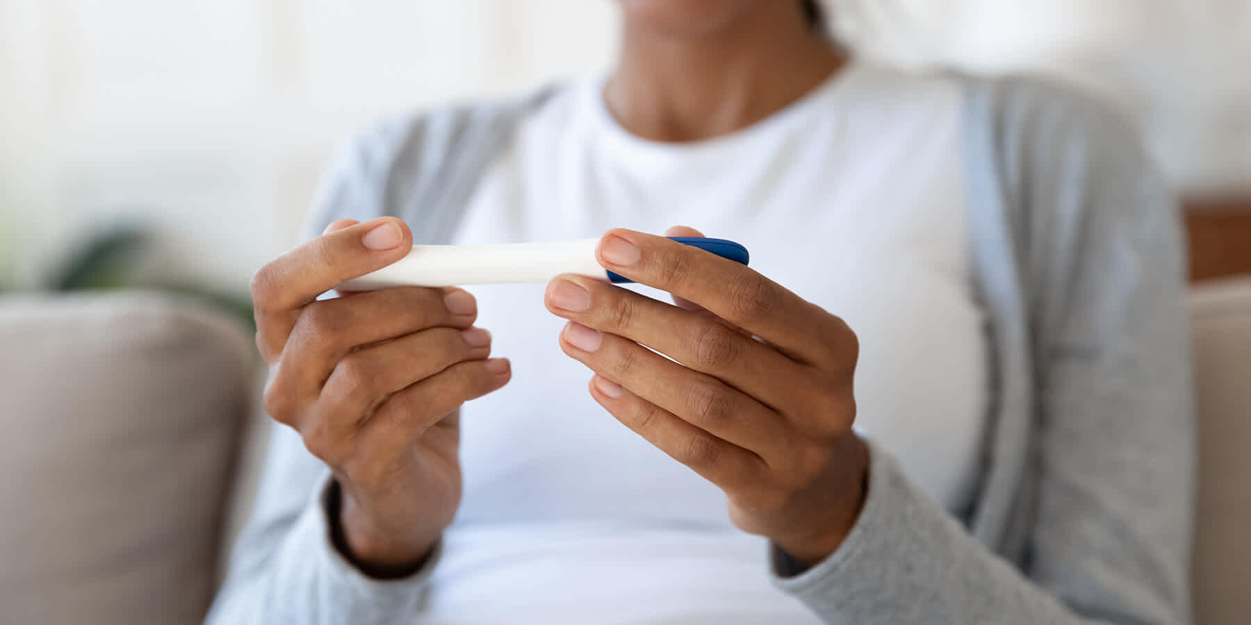 Woman holding a pregnancy test in her hands and looking at the result while wondering about FSH levels