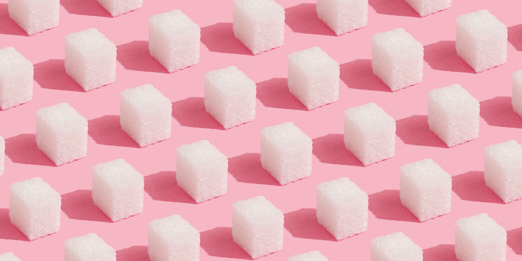 Cubes of sugar against a pink background to represent sugar that may contribute to inflammation