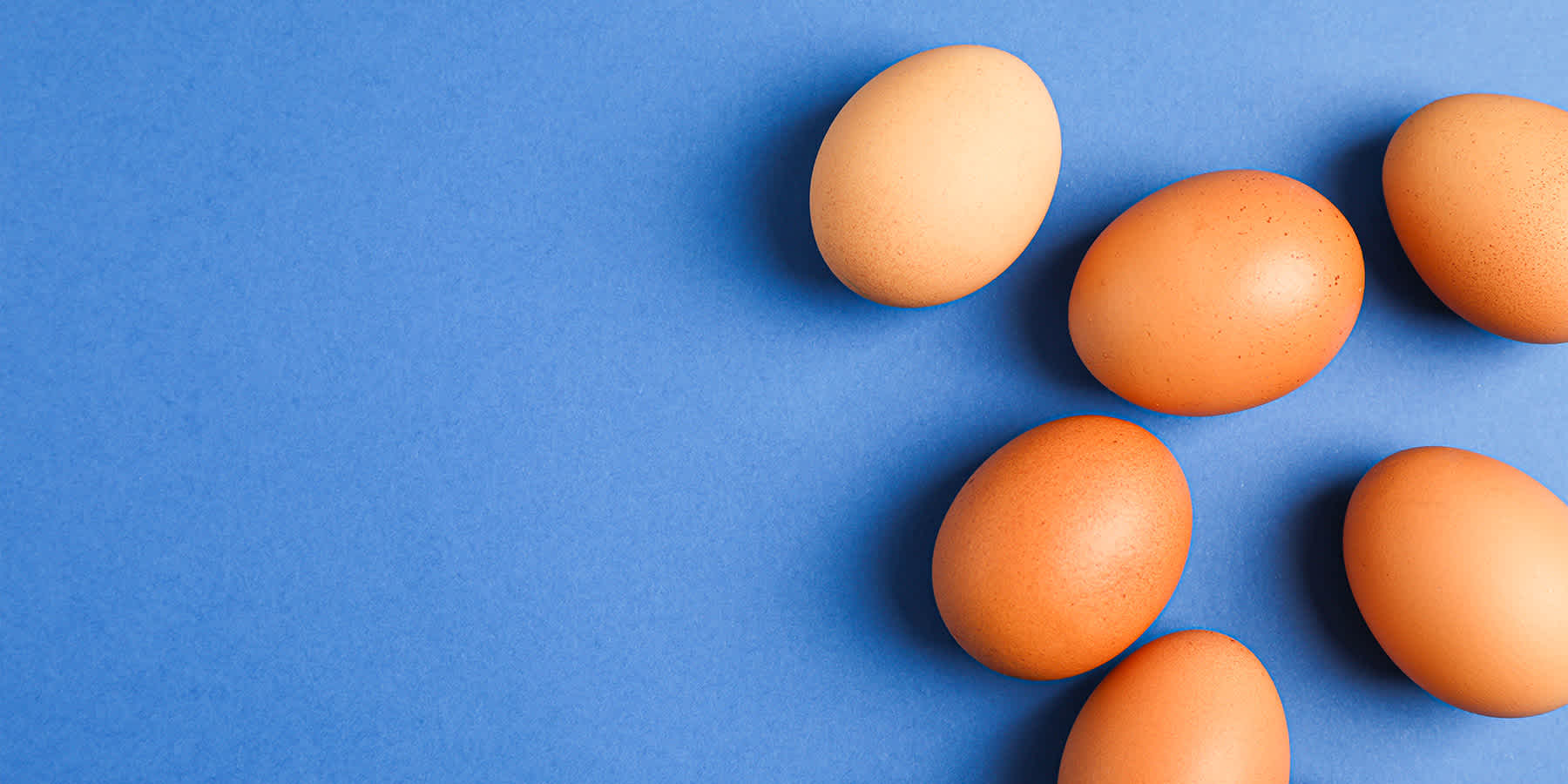 Several eggs against a blue background as an example of a food for a low fructose diet