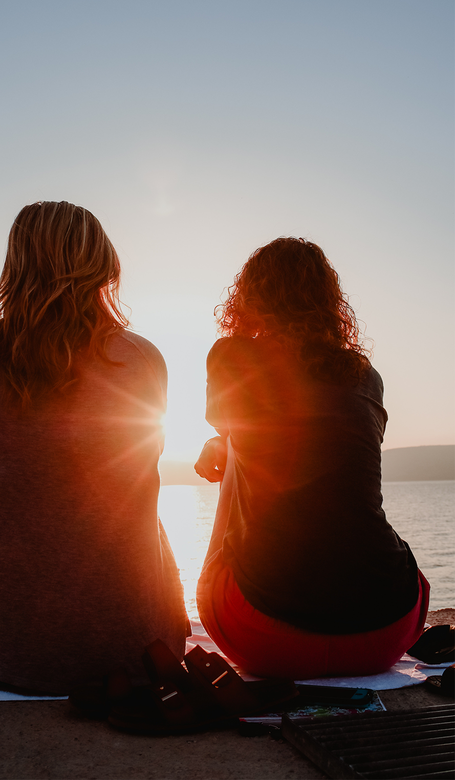 Two women looking at the sunset and talking about HPV