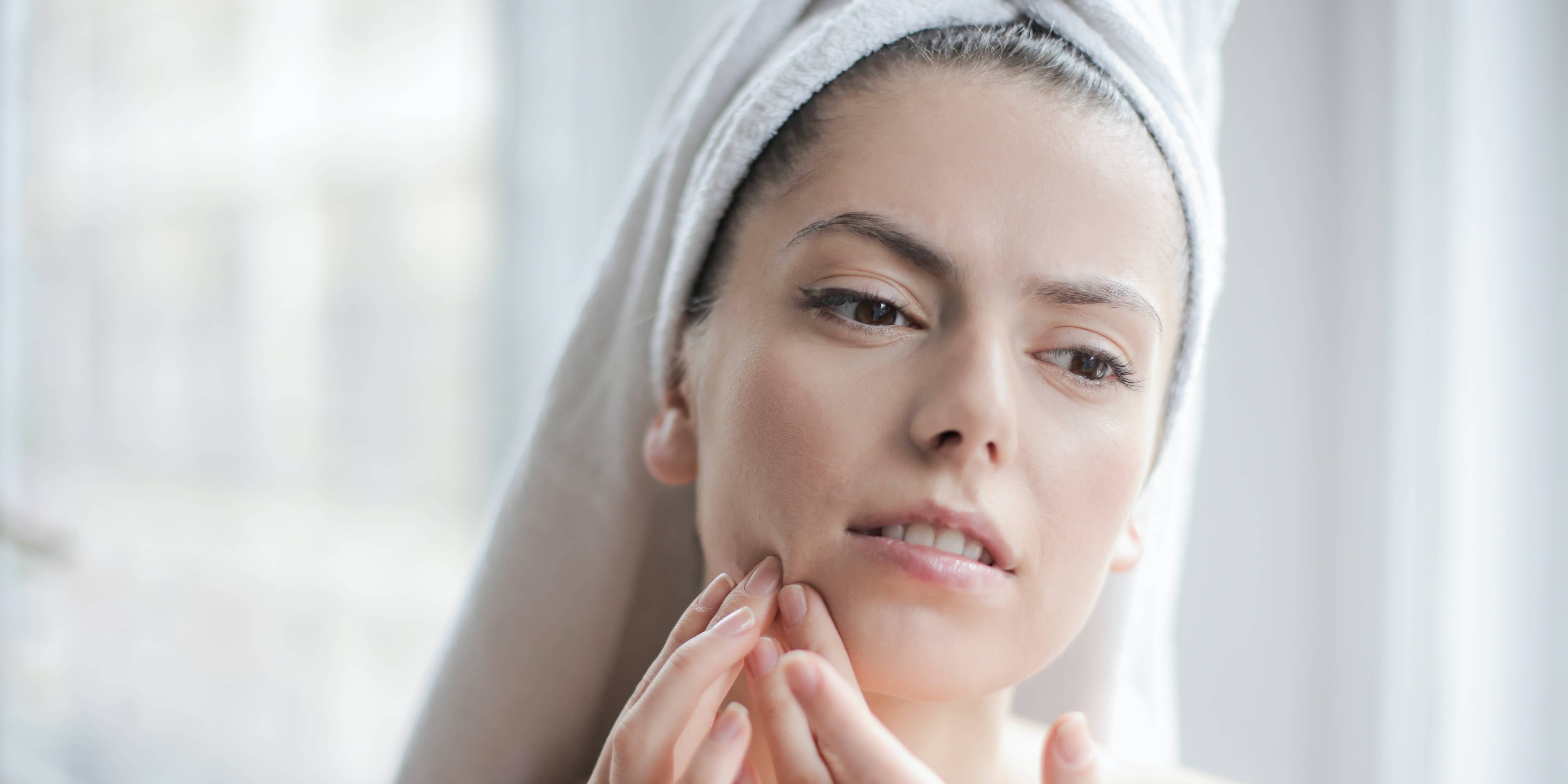 Woman looking at skin issue while wondering about online help with skin issues