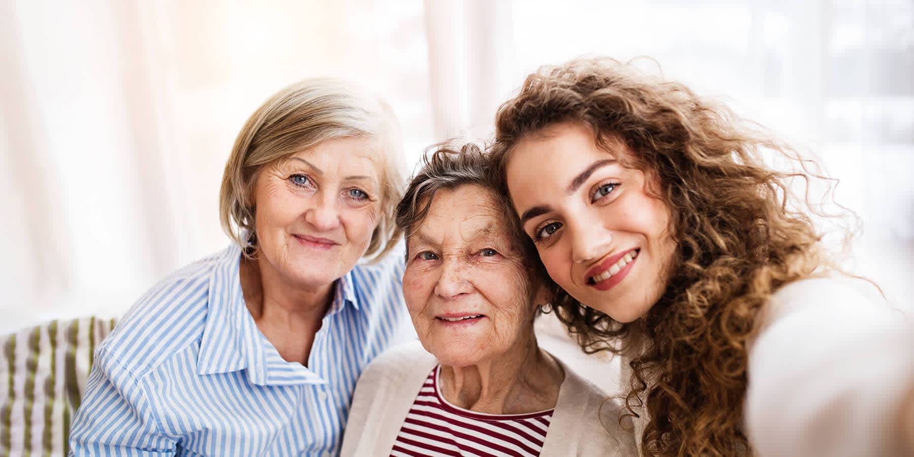 Daughter, mother, and grandmother smiling together to represent genetic inheritance