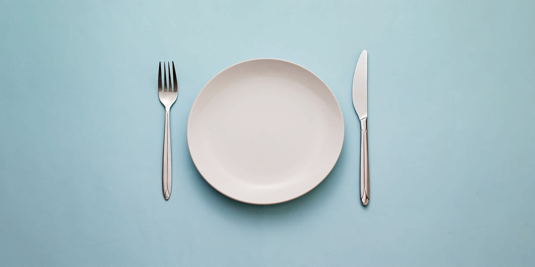 Empty plate and silverware on blue background
