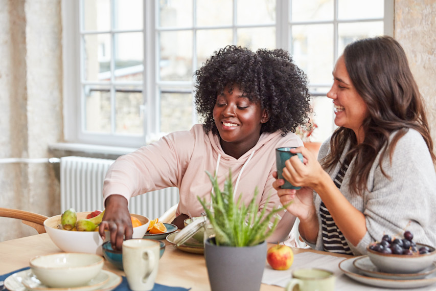 two women sitting at a table with food and coffee