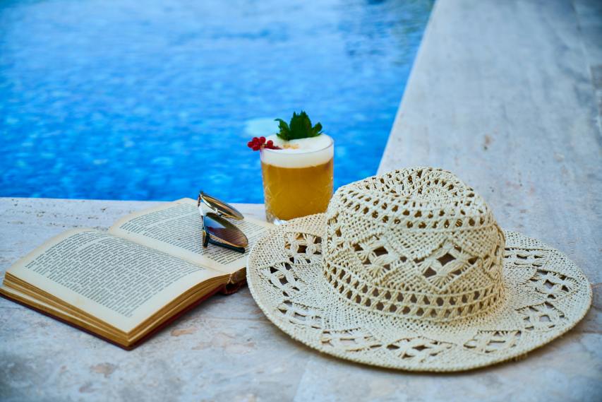 Book, drink, and hat poolside.