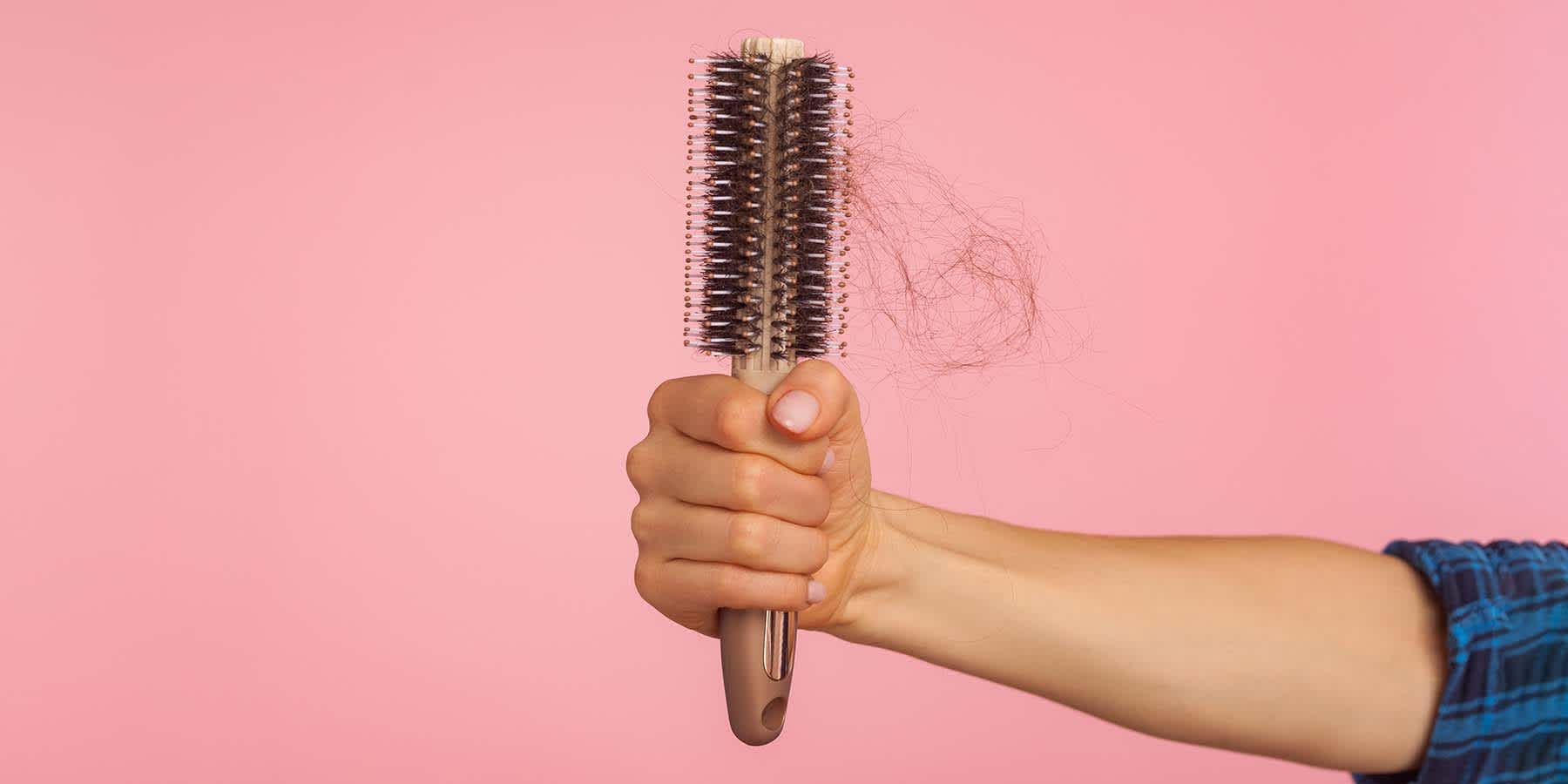 Stressed woman holding brush with hair