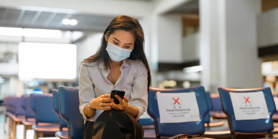 Woman wearing face mask sitting in social distanced waiting room
