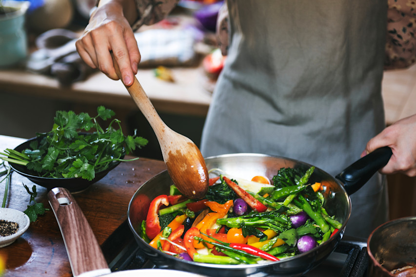 person cooking vegetables in a pan