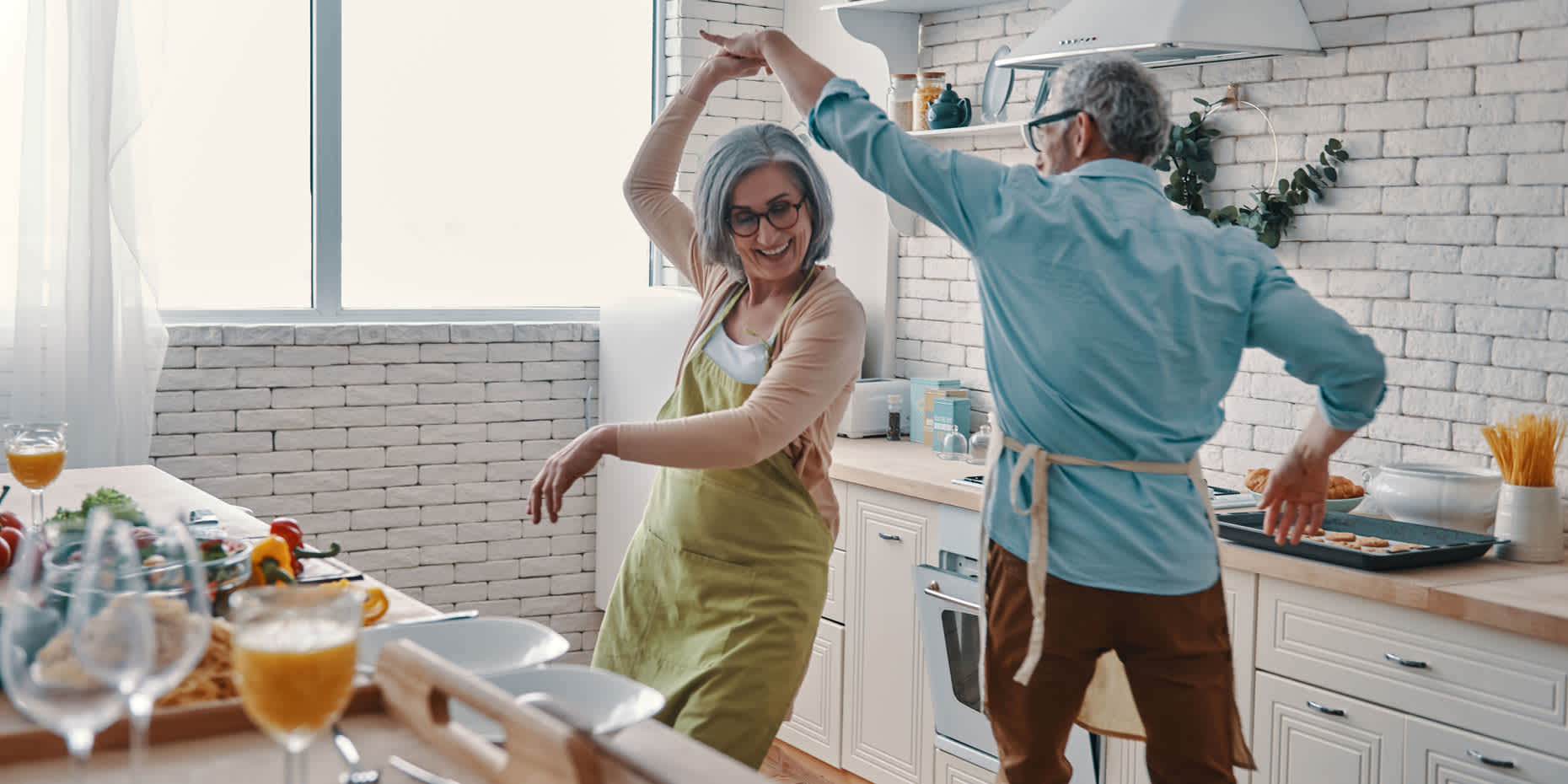 Happy elderly couple dancing together in the kitchen