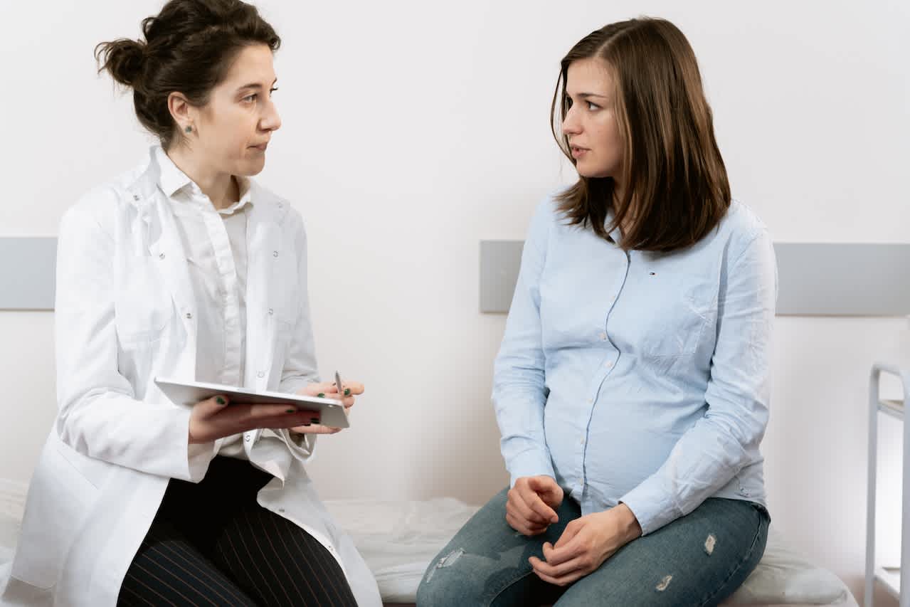 Healthcare provider with pregnant patient discussing the difference between pregnancy bloating vs. period bloating