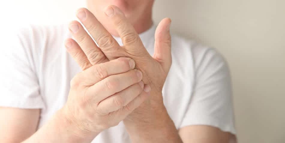 Close up of a man holding his left hand with his left arm tingling