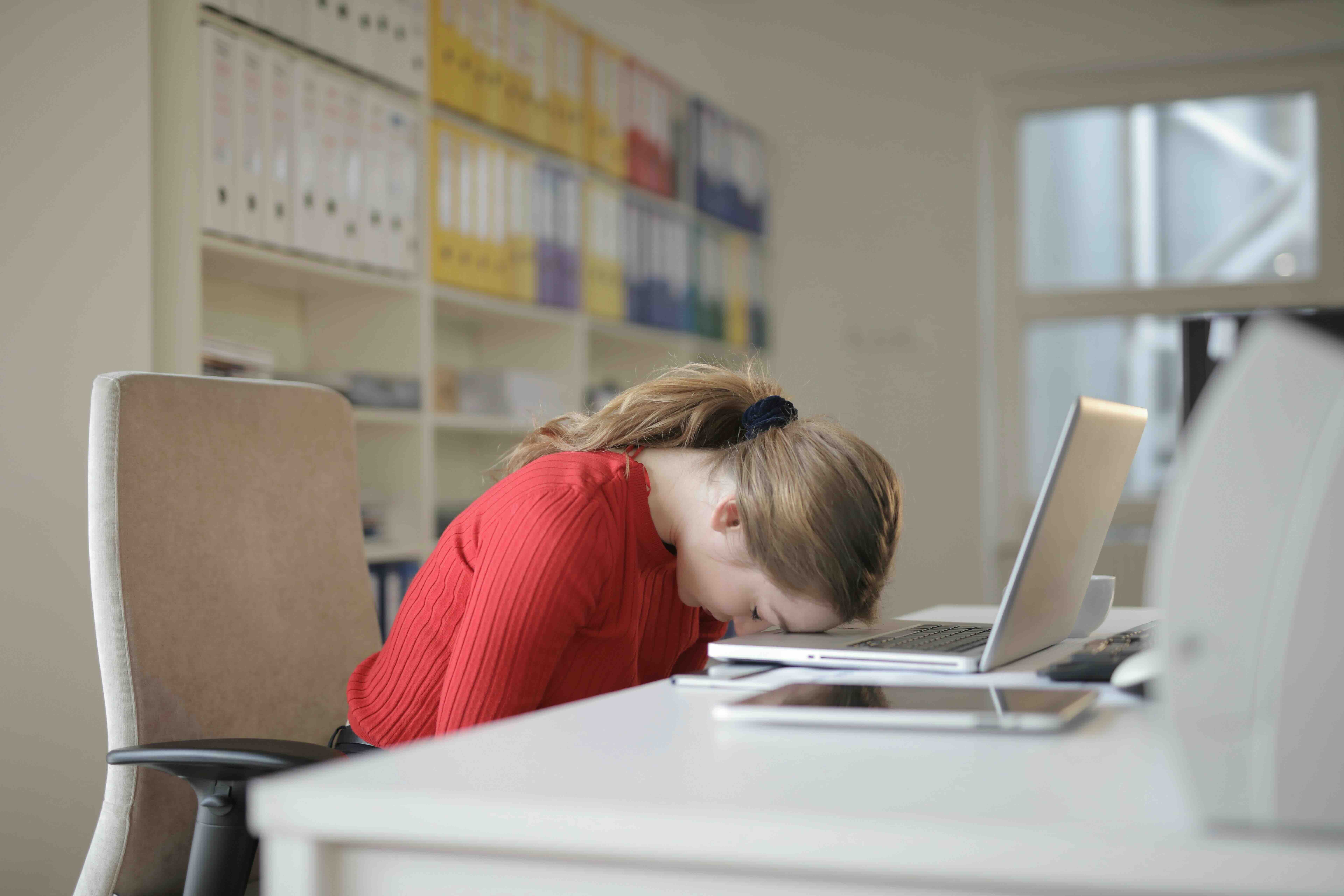 Young woman resting her head on table while wondering whether antibiotics make you tired