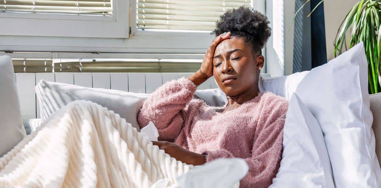 Young woman resting on couch after receiving flu treatment at home