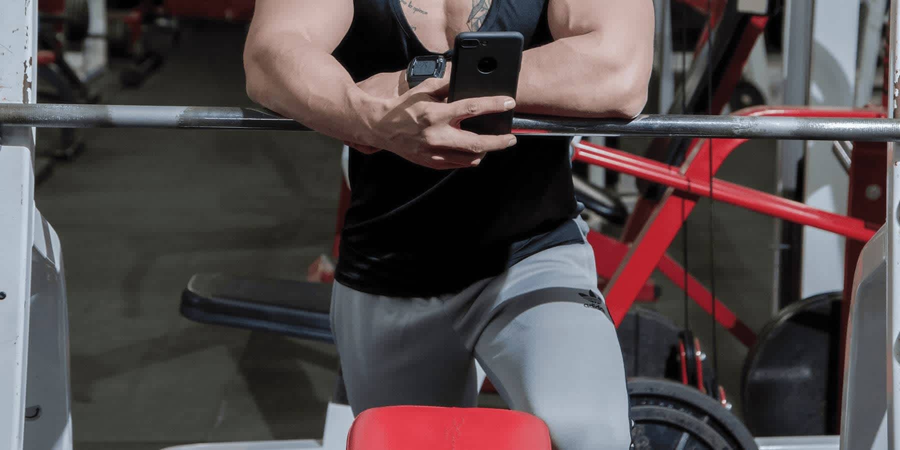 Man at gym with mobile phone looking up the difference between free T vs. total T