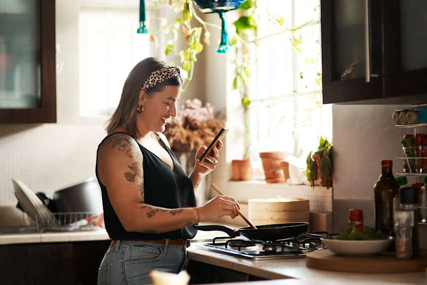 Woman cooking and looking at phone