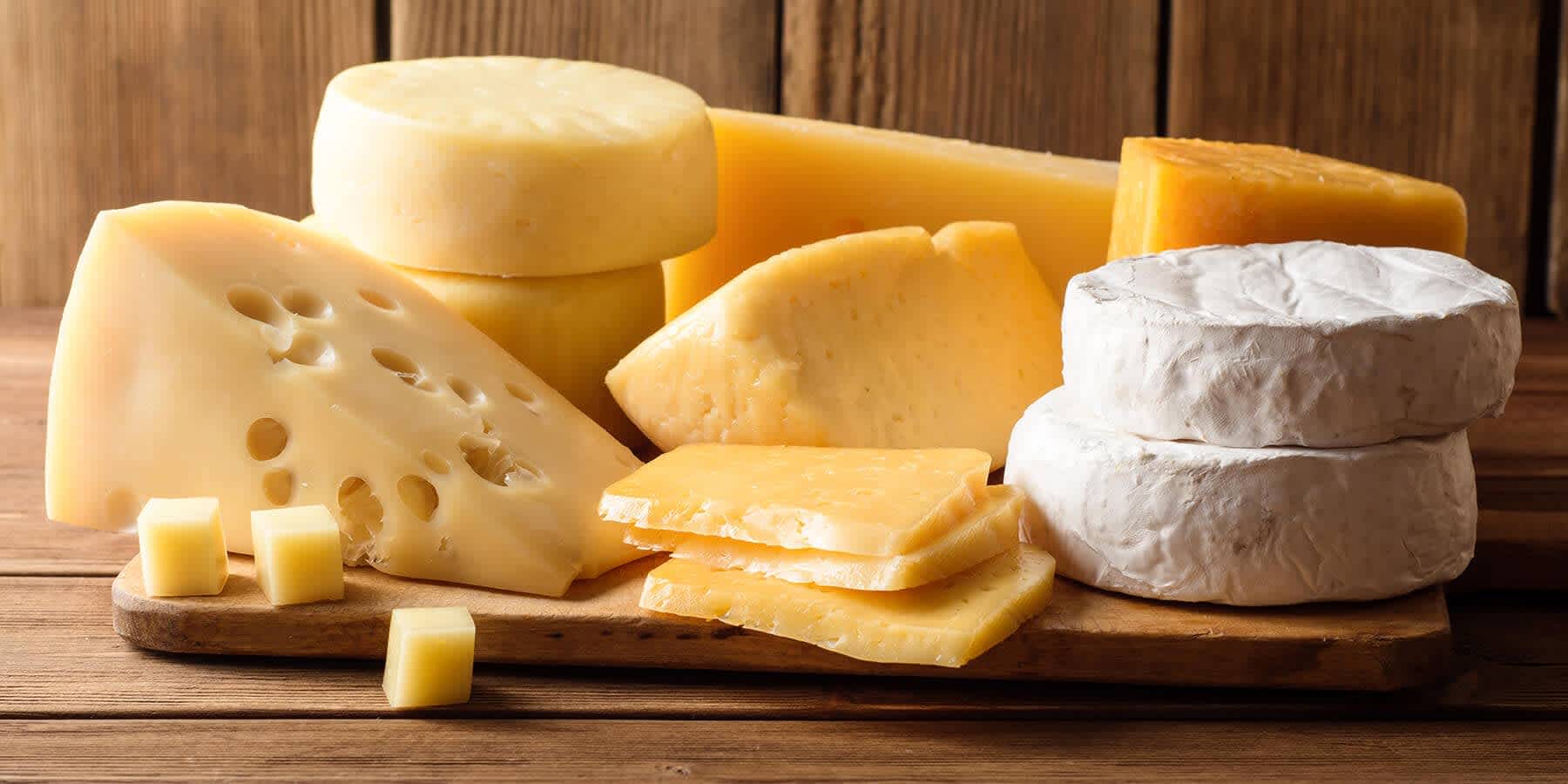 Variety of cheeses on wooden table to represent worst foods for high cholesterol