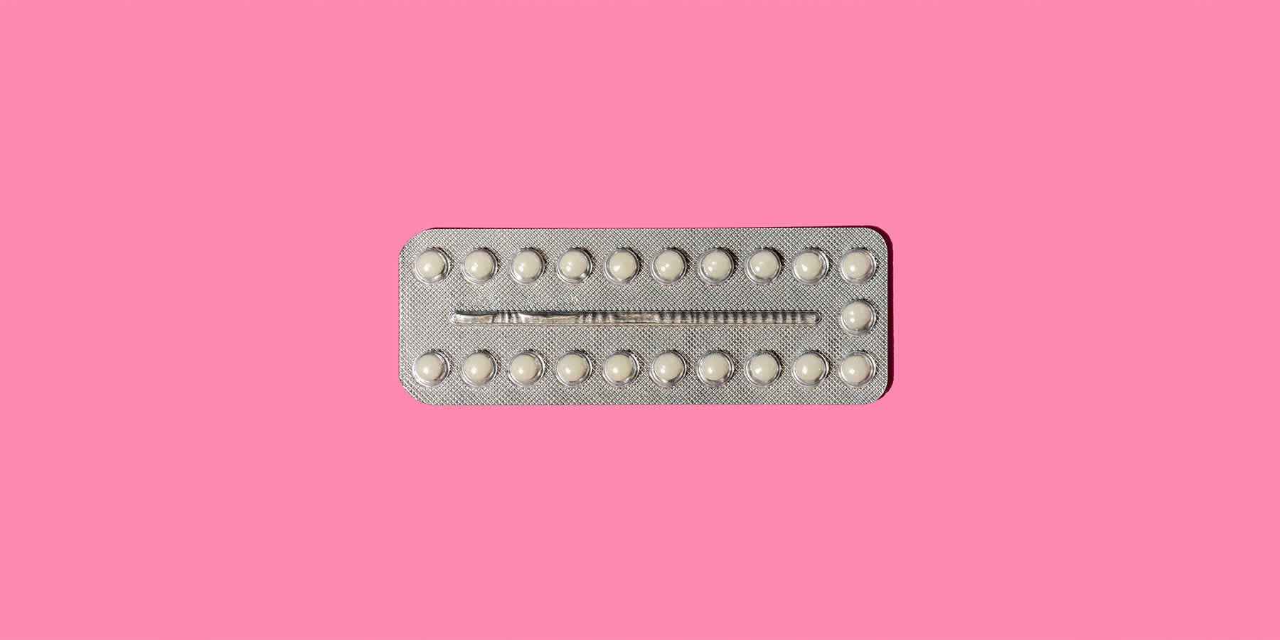 Packet of birth control pills against a pink background