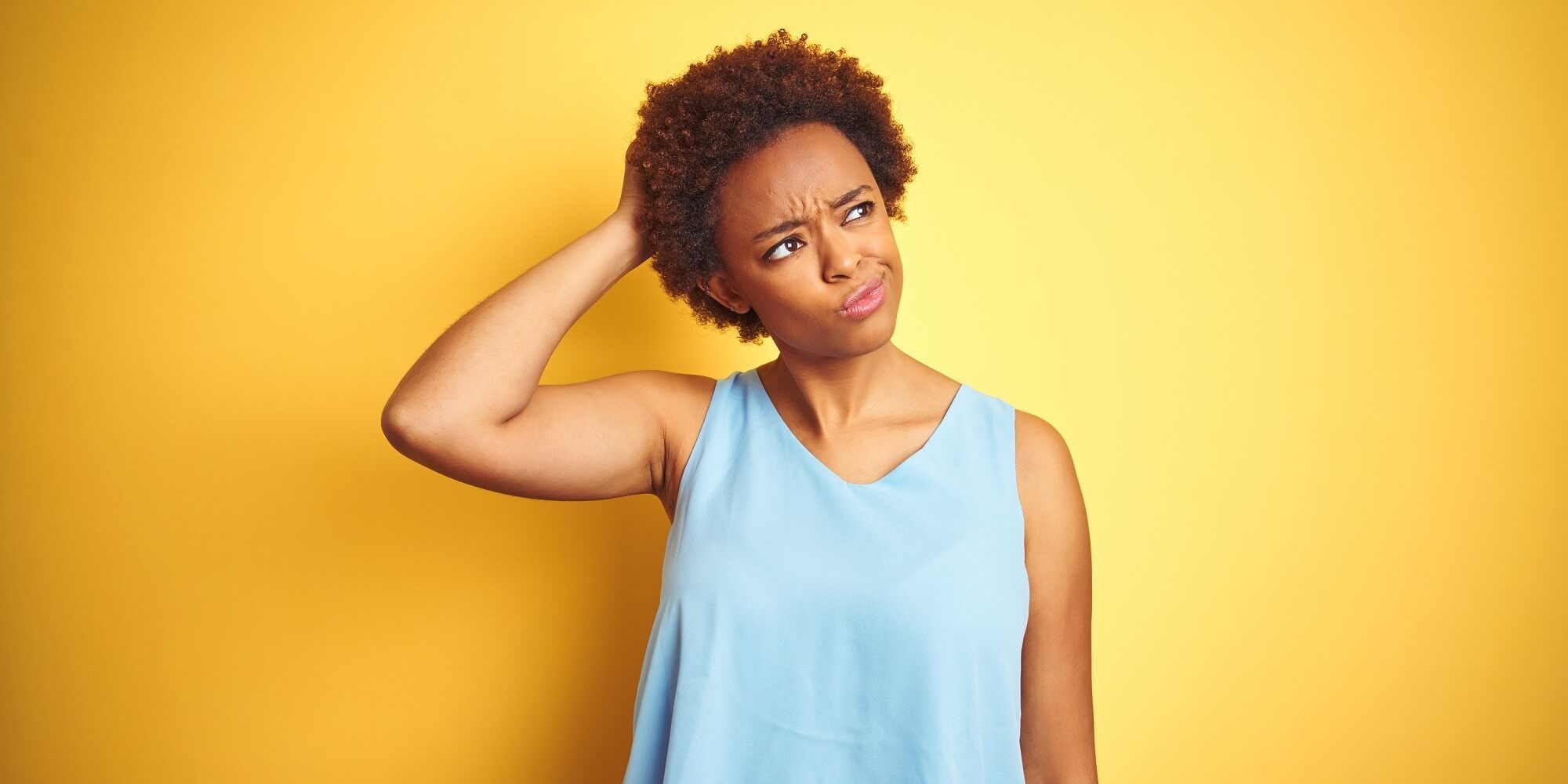 Young woman scratching her head and wondering about vaginal dryness and what causes lack of wetness