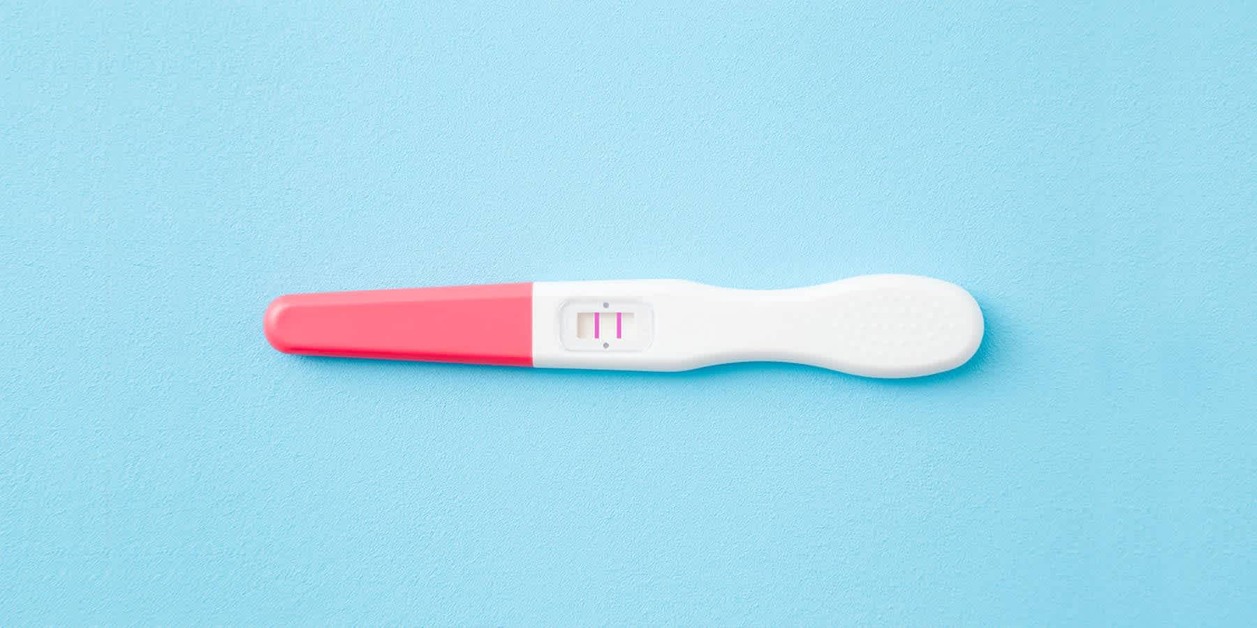 Positive pregnancy test on a blue background to highlight link between B12 status and pregnancy outcomes