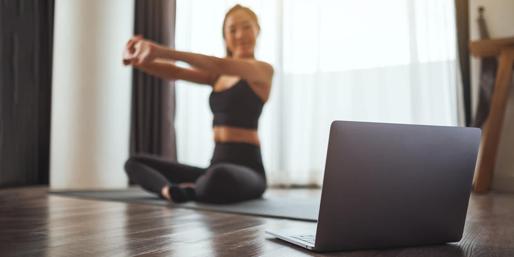 Woman exercising while setting up laptop for asynchronous telehealth