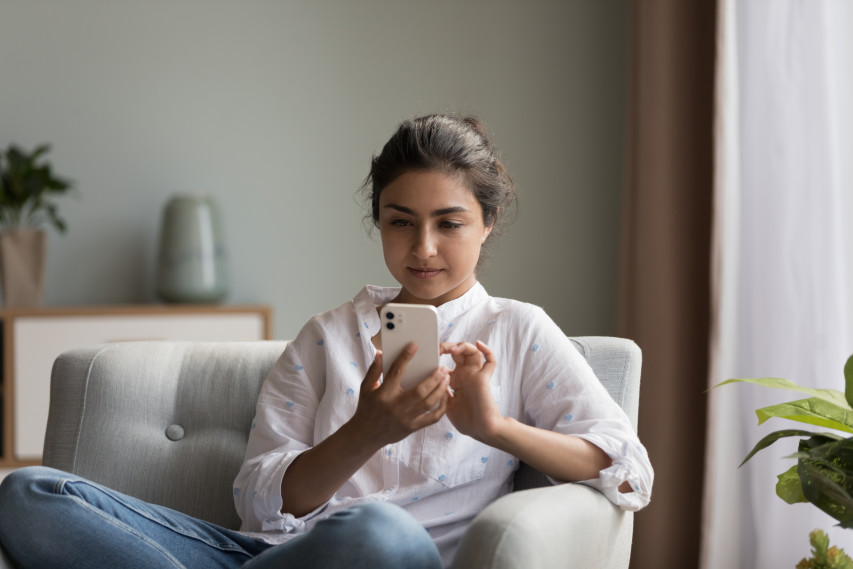 woman sitting on couch and looking at phone