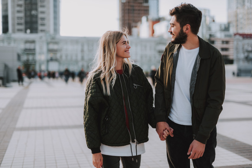 man and woman walking in city holding hands