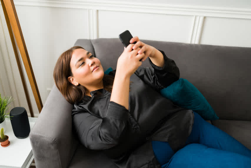 woman lying on couch looking at phone