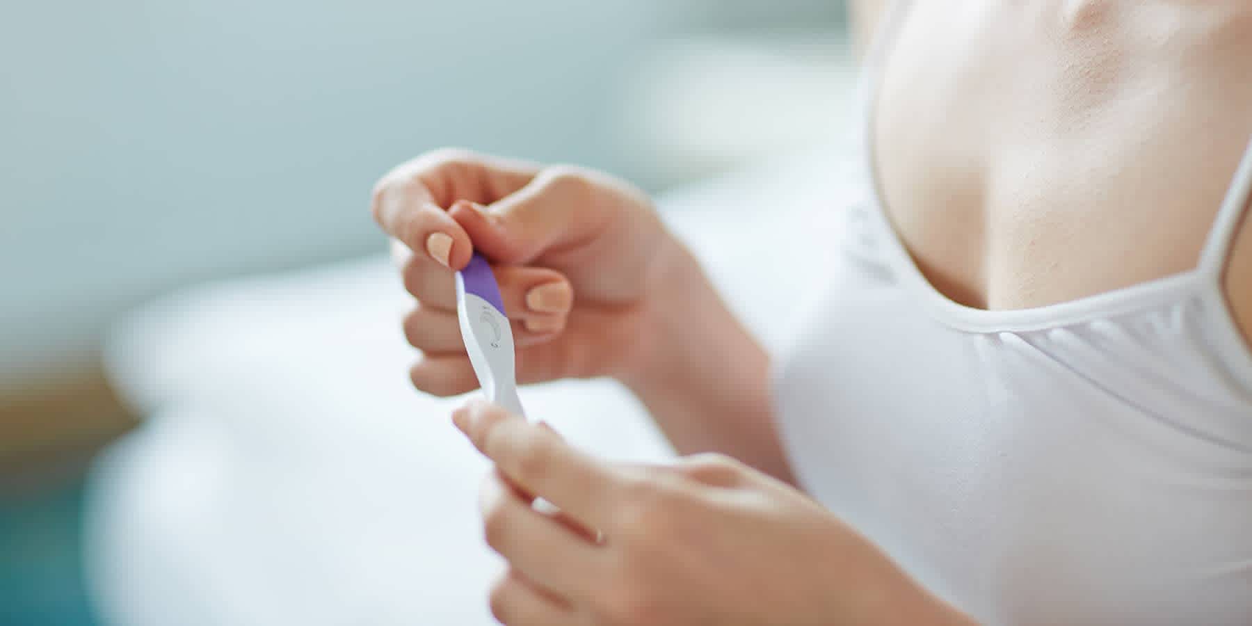 Woman looking at a pregnancy test after testing fertility hormones at home