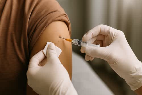 Healthcare professional giving a vaccine injection in the upper arm, representing immunization and preventable disease protecti