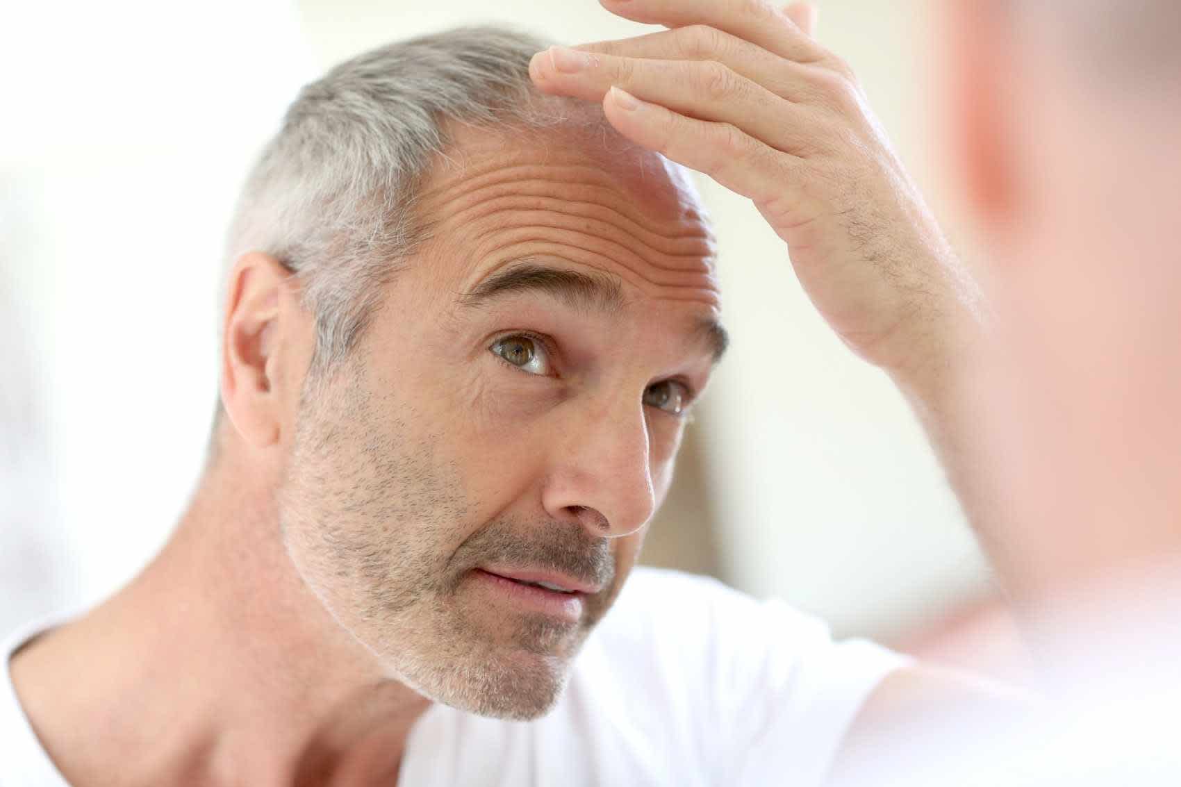 Man over 60 looking at mirror before virtual healthcare appointment