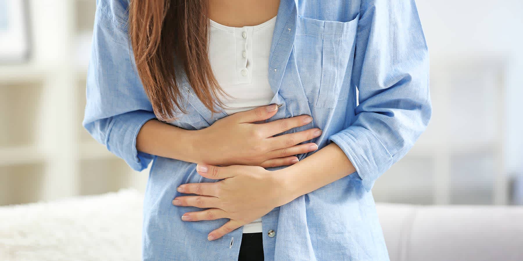 Woman experiencing abdominal pain as a common food allergy symptom