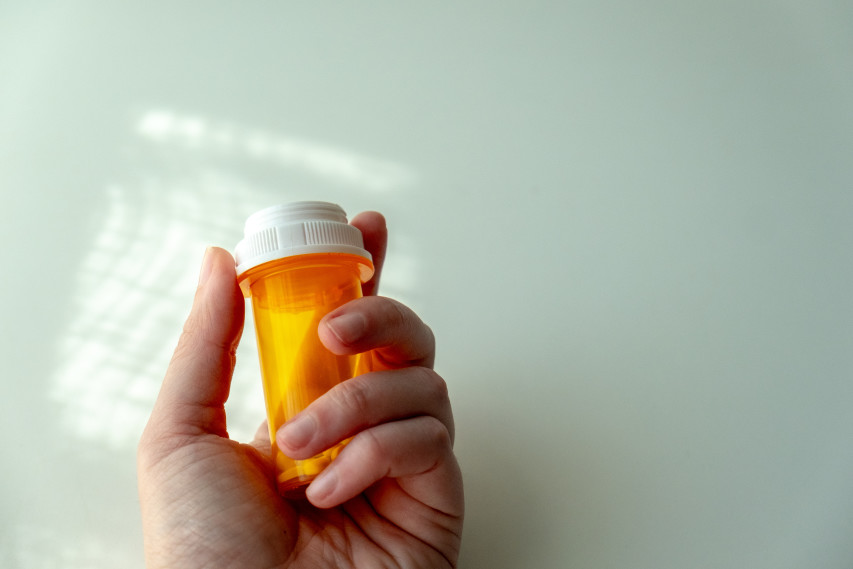 hand holding pill bottle against table with light