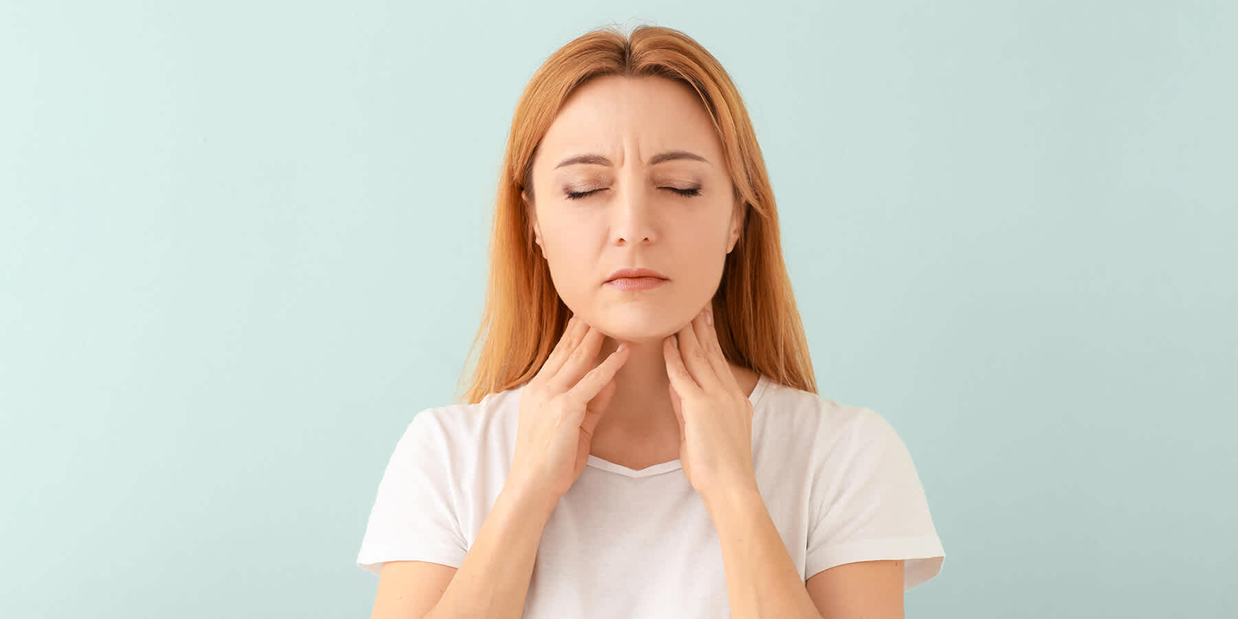 Young woman feeling her neck while wondering what a heterogeneous thyroid means