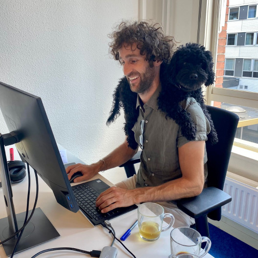 Fourthline member working at desk with dog on shoulders