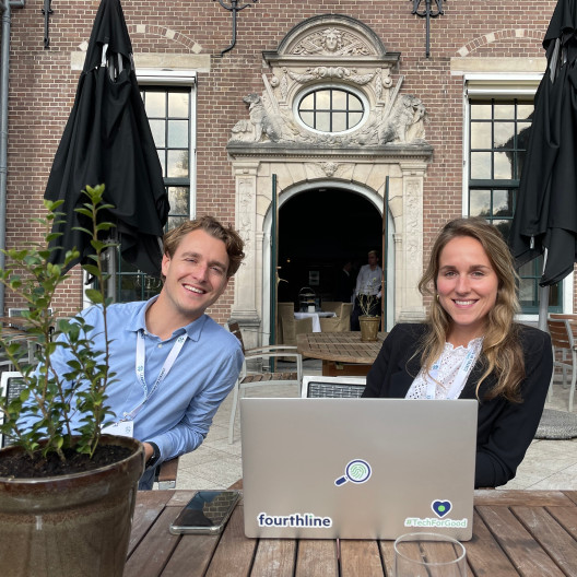 Fourthline 2 members sitting outside at table with laptop 