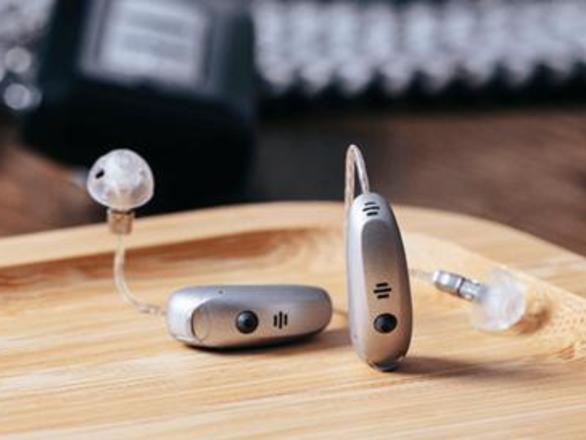 Two Receiver in canal hearing aids showcases on a wooden table