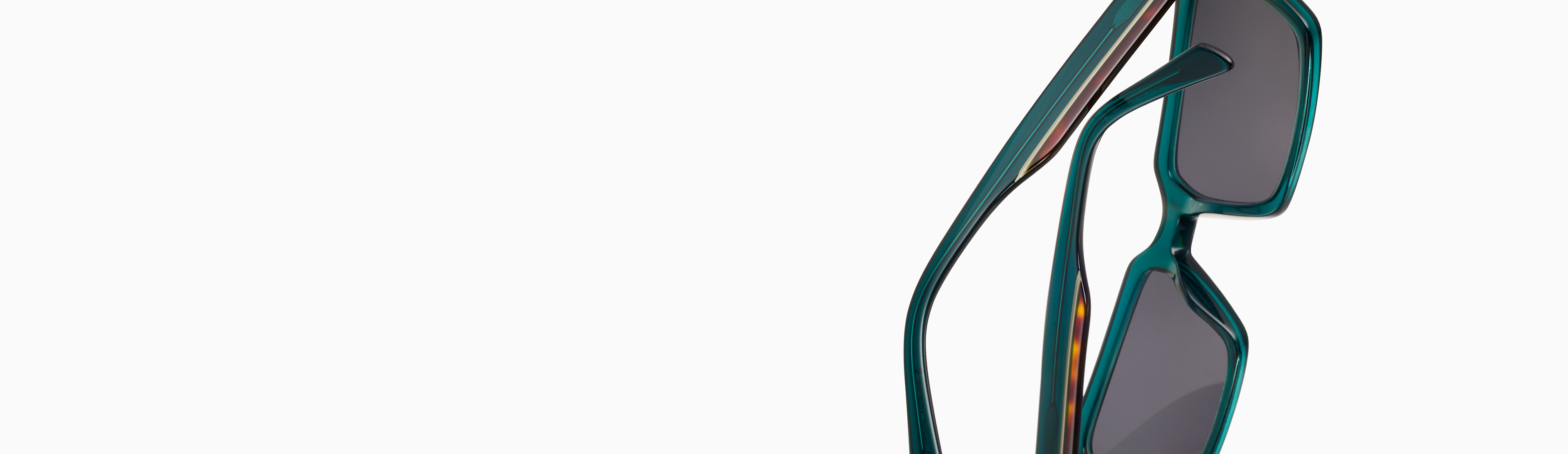 Close-up image of stylish, teal-colored sunglasses with dark lenses and a modern geometric frame design