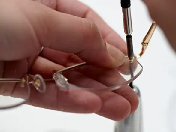 Close up image of pair of hands fixing a pair of glasses.