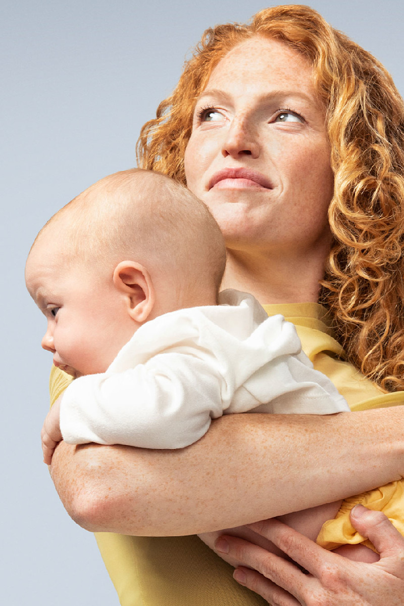 Model holding young baby in her arms.