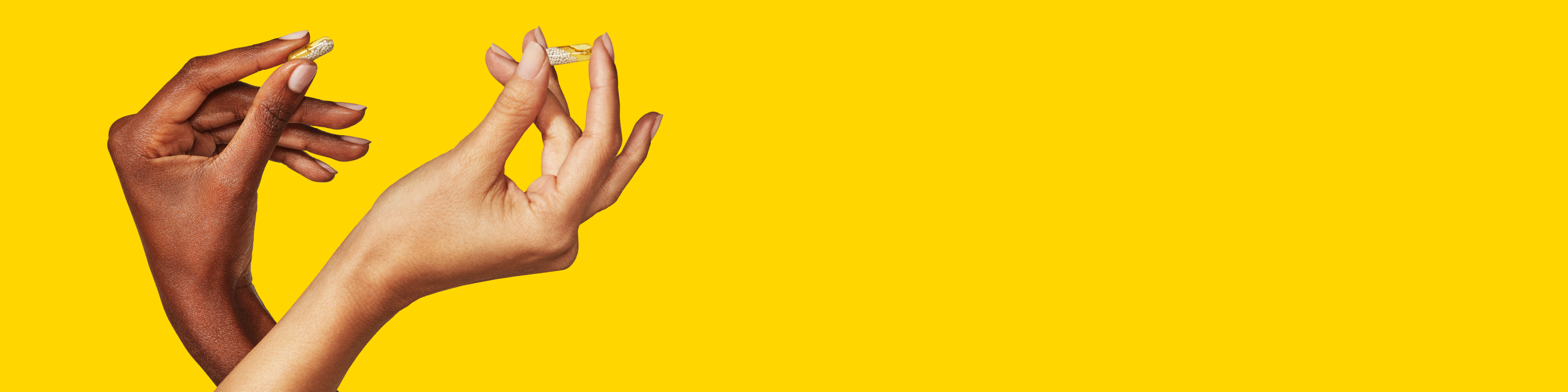 Two multivitamin capsules in two separate hands