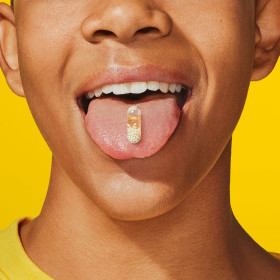 Teen boy model taking Essential for Teens Multivitamin for Him pill