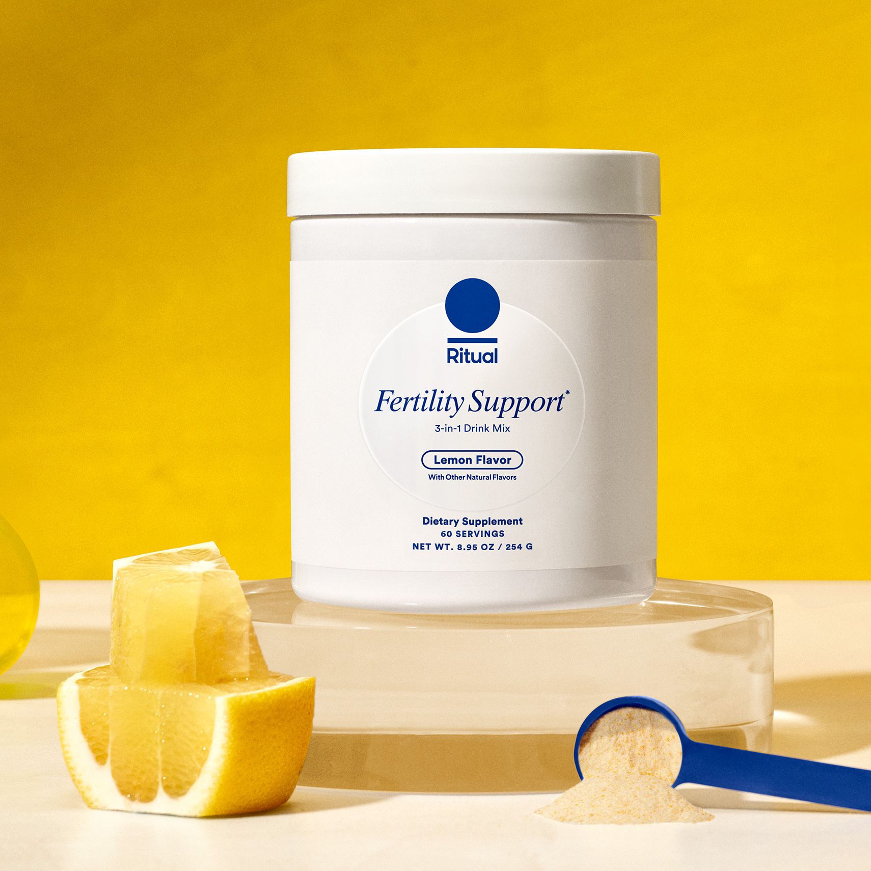 Jar of Ritual's Fertility Support with a yellow background and blue scoop with the powdered product in the foreground. 