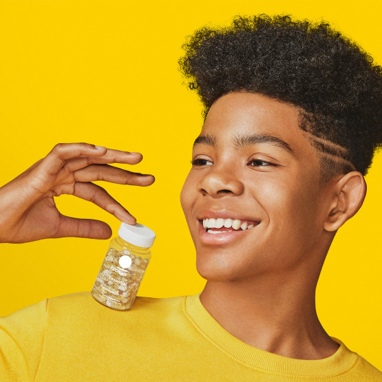 Teen boy model holding a bottle of Essential for Teens Multivitamin for Him