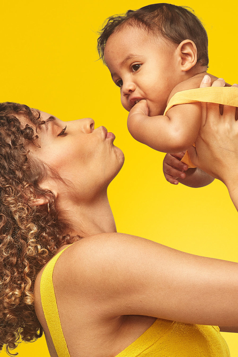 Model holding young child making a playful face.