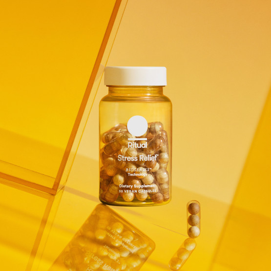 Stress Relief bottle next to a Stress Relief capsule on a yellow and orange background.